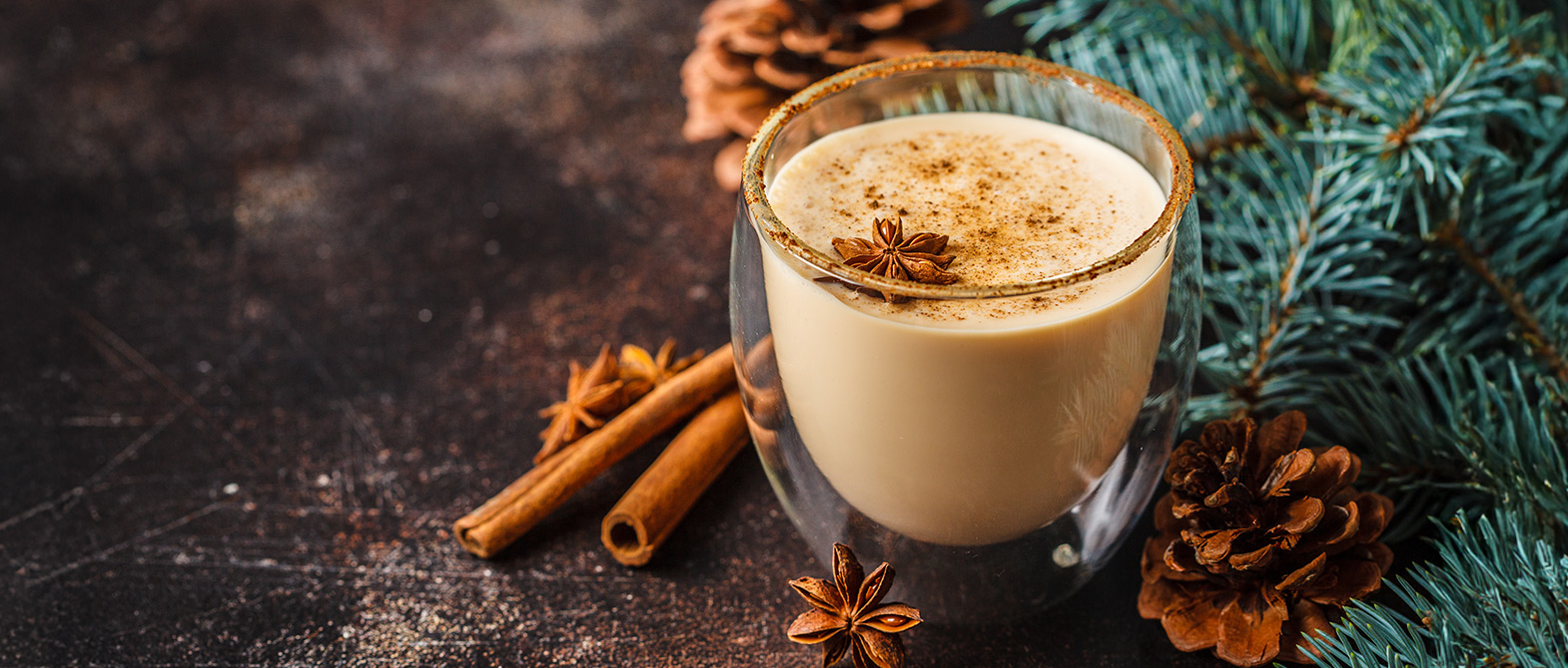 Delicious and creamy Christmas holiday spiced dessert cocktail with evergreen and pinecone